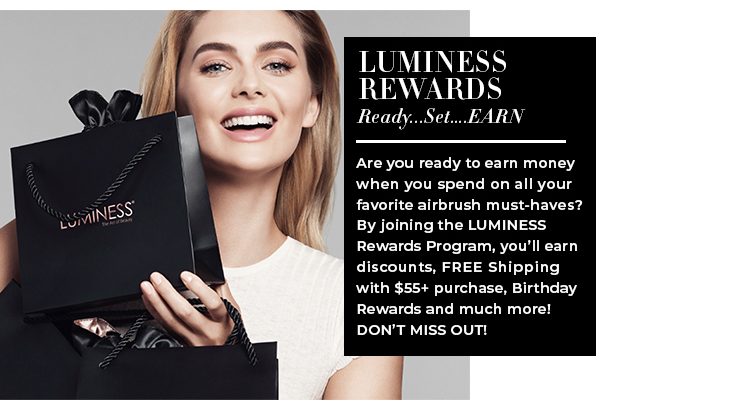Caucasian model, smiling holds a black Luminess shopping bag